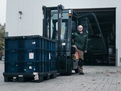 Mann mit Gabelstapler vor einer Lagerhalle