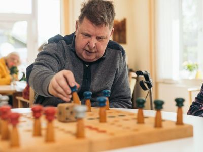 Mann spielt ein seniorengerechtes Brettspiel