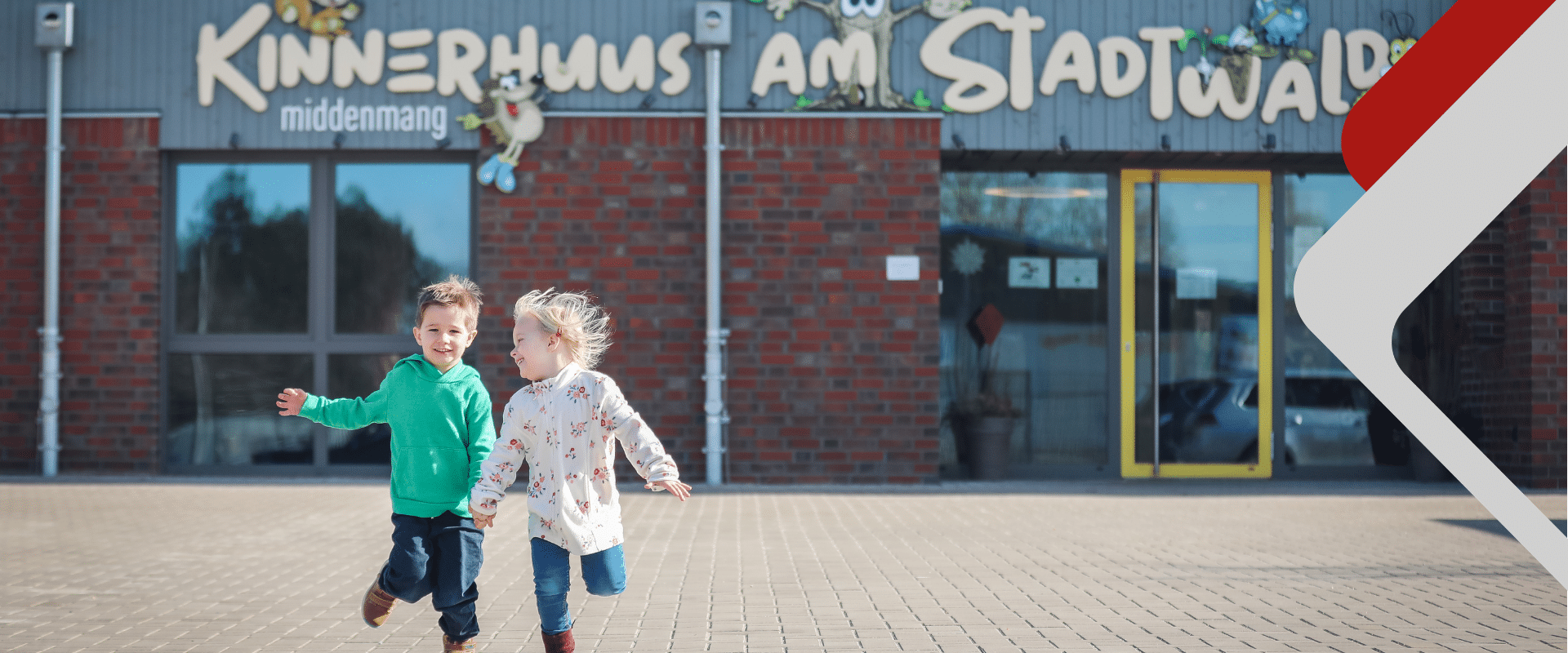 zwei Kinder laufen vor der Kita auf die Kamera zu