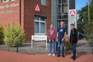 3 Teilnehmende des Schichtwechsels stehen vor der Agentur für Arbeit in Emden.